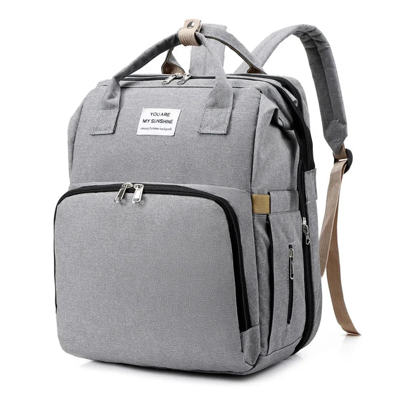 A gray backpack diaper bag with a zippered front pocket and a carrying strap.