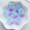 A collection of translucent blue and purple resin charms shaped like sea creatures for crafting and jewelry making