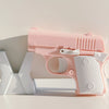 A pink mini 3D printed gravity fidget pistol toy resting on a white surface.