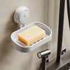 A white suction cup soap dish holder with a removable tray is mounted on a wall, next to a white light switch.