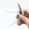 A hand holds an adjustable guitar capo with a built-in bridge pin puller tool.