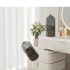A white and gold rotating makeup brush holder with a dark gray dustproof lid displayed on a vanity table.