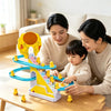 A family is playing with a yellow duck stair climbing track toy on a wooden table.