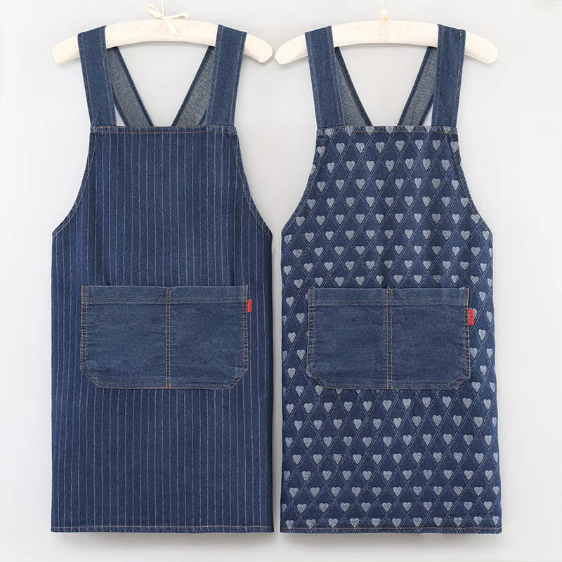 A pair of navy blue striped denim cross-back aprons displayed on a hanger.