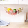 Macrame hanging fruit hammock filled with colorful fruits suspended on a shelf