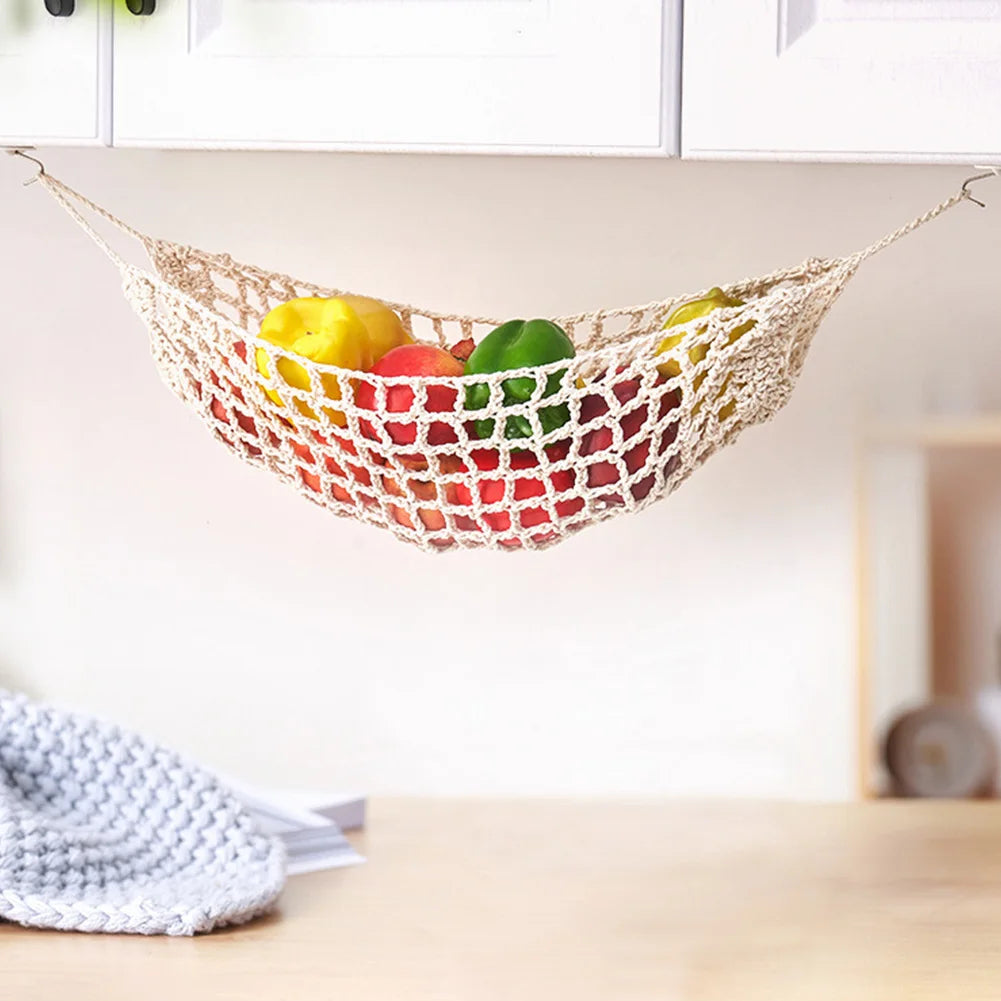 Macrame hanging fruit hammock filled with colorful fruits suspended on a shelf