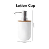 A white lotion cup with a metal dispenser and a bamboo base.