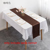 Elegant brown satin table runner set for events featuring white plates and floral accents