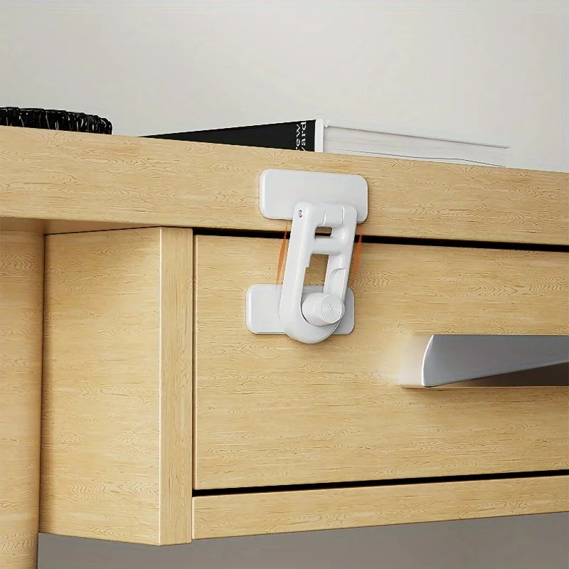 A close-up of a light wood cabinet drawer with white non-drill child safety door locks installed on the front.