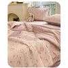 A pink cartoon pattern kids lightweight summer quilt displayed on a bed with a light-colored headboard.