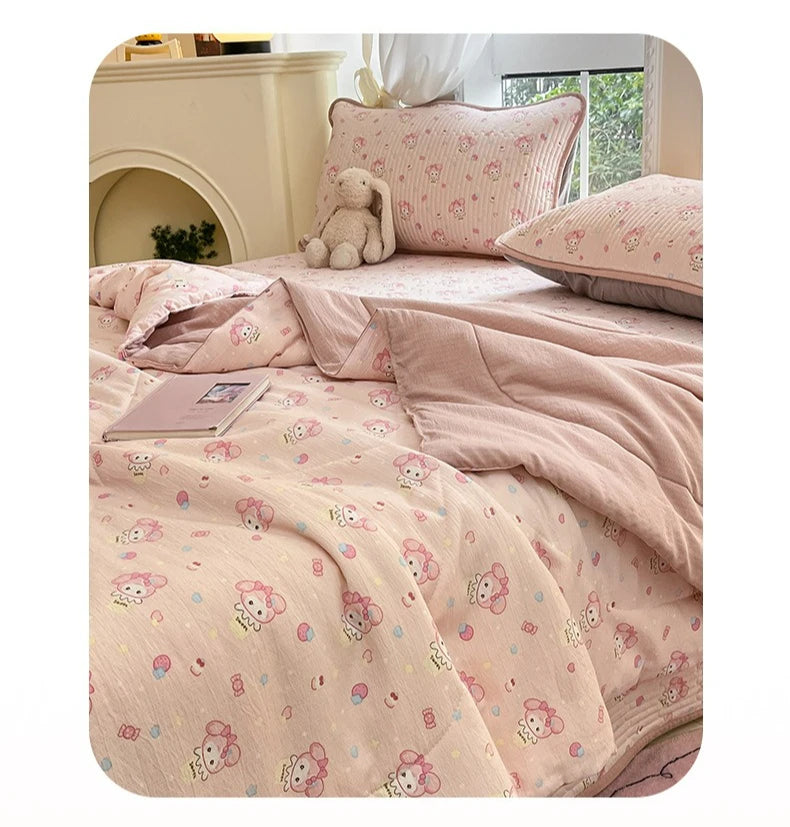 A pink cartoon pattern kids lightweight summer quilt displayed on a bed with a light-colored headboard.