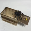 A wooden box with a pop-out trick toy spider inside.