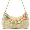 A beige straw shoulder bag with gold chain straps adorned with colorful ocean shell charms.