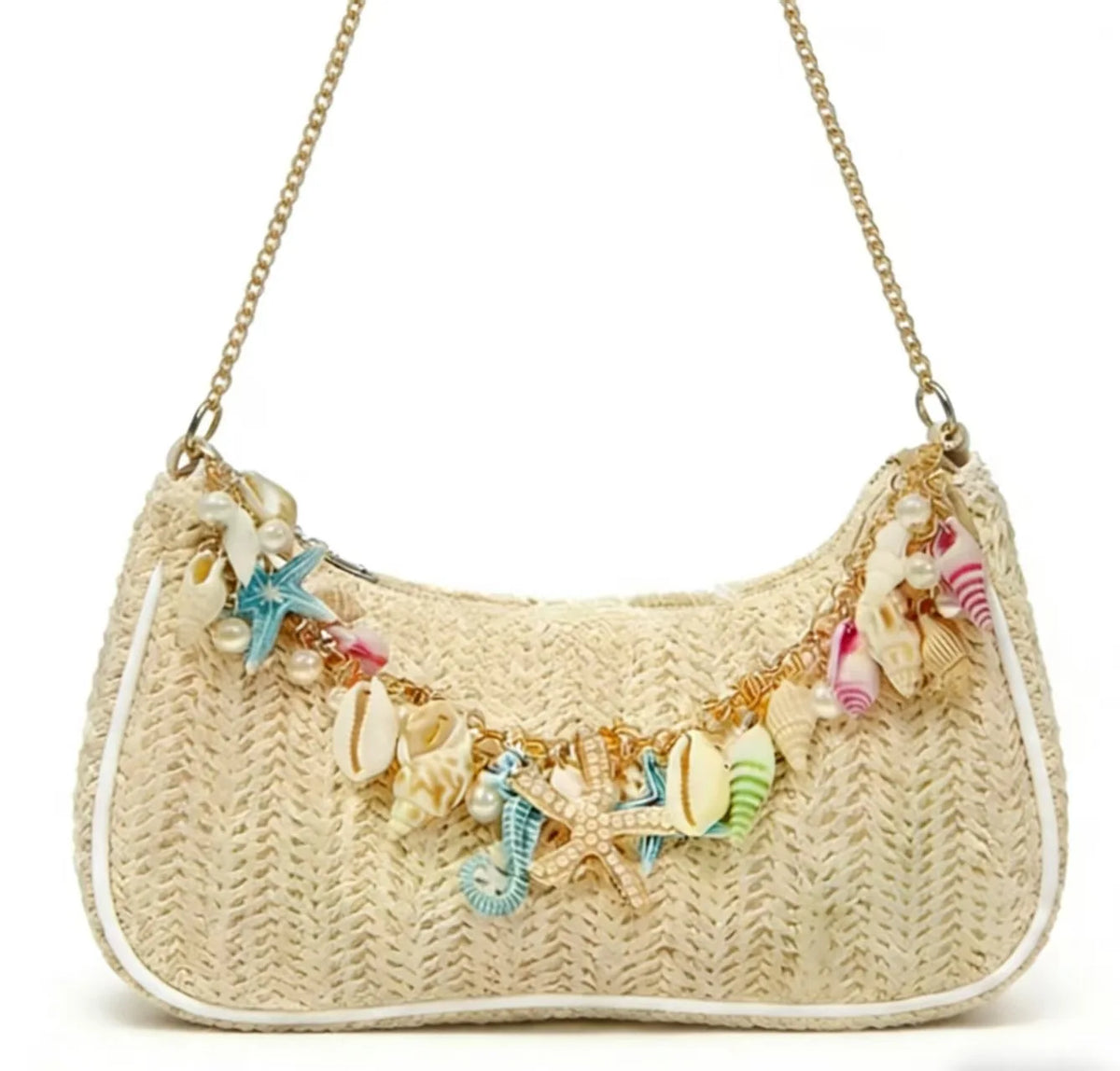A beige straw shoulder bag with gold chain straps adorned with colorful ocean shell charms.