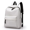 A white minimalist canvas backpack with black trim and straps shown from the front.