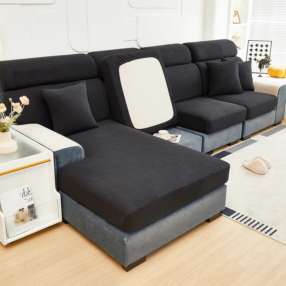 A dark gray elegant jacquard sofa slipcover with an elastic fit displayed indoors.
