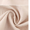 Close-up of a beige premium cotton kitchen apron fabric showing soft folds and texture.
