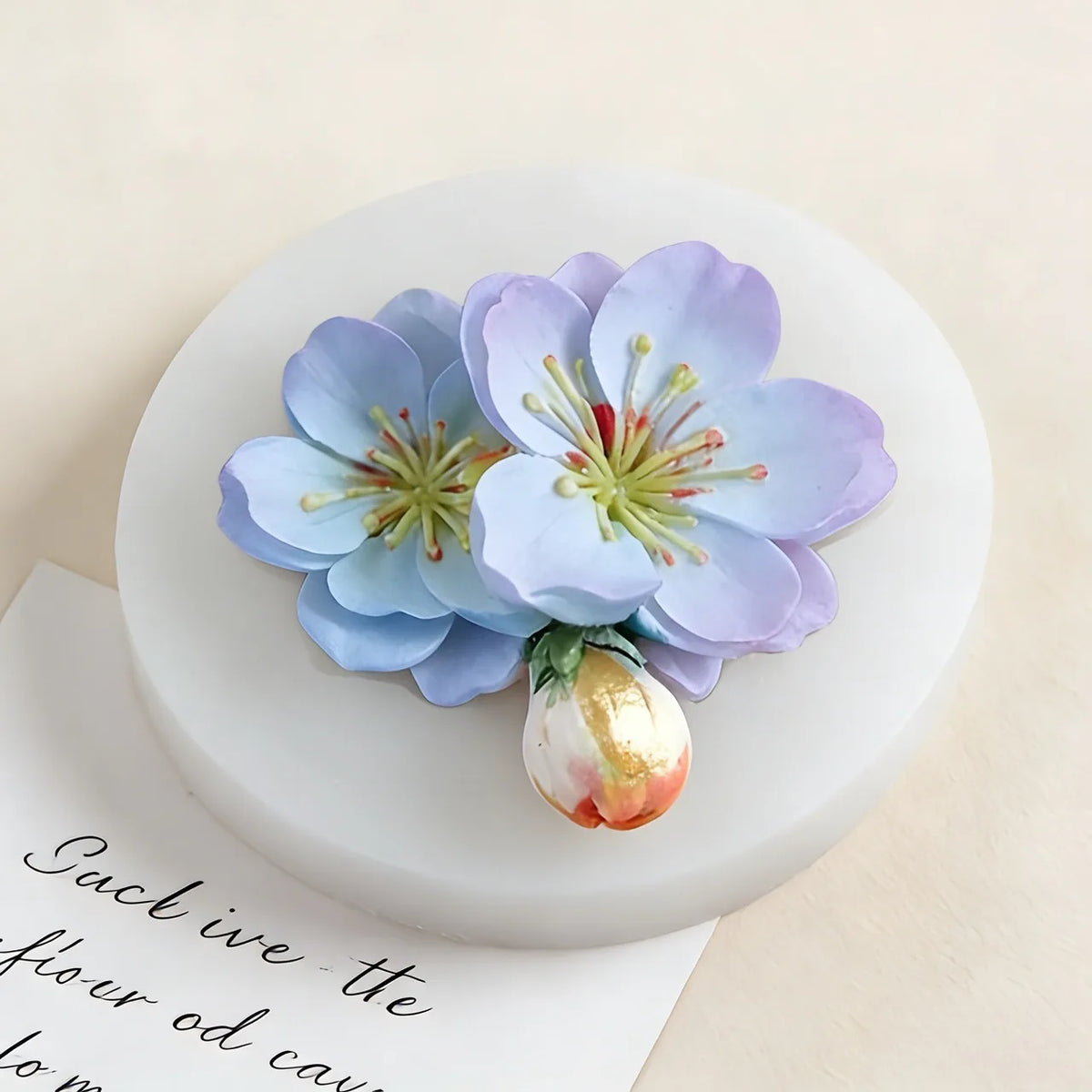 A light blue lotus flower silicone mold with green stamens rests on a white circular surface.