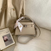 Beige elegante PU-Leder-Clutchtasche auf hellem Stoffhintergrund.