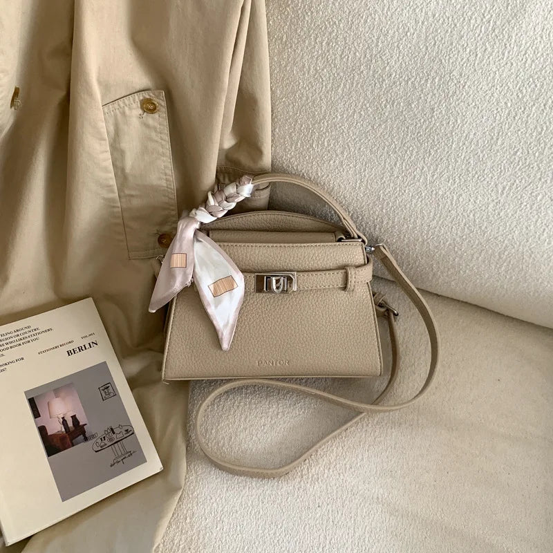 Beige elegante PU-Leder-Clutchtasche auf hellem Stoffhintergrund.