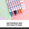 A collection of paint markers in various colors and finishes, including gold, silver, black, and white.