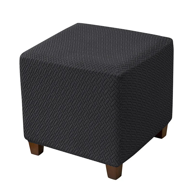A dark gray stretch jacquard ottoman slipcover with an elastic edge shown from the side.