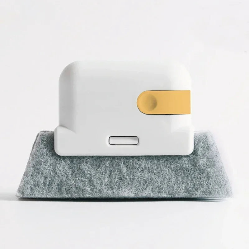 A white groove cleaning brush with a gold scouring head resting on a gray felt surface.