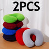 Two green, red, blue, and white inflatable U-shaped travel neck pillows displayed on a wooden surface.