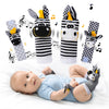 A set of black and white striped baby wrist rattles and foot finder socks with yellow accents shown above a baby lying on a w