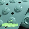 A close-up view of a light green non-slip bath mat featuring raised massage nodes.