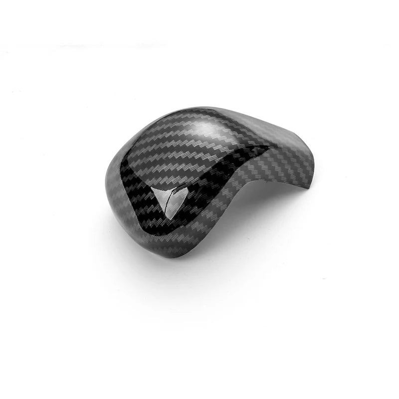 A close-up view of a carbon fiber gear shift knob cover with a black and gray weave pattern.