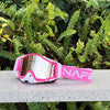 Pink and white HD motocross goggles with anti-fog lenses resting on a gray surface.