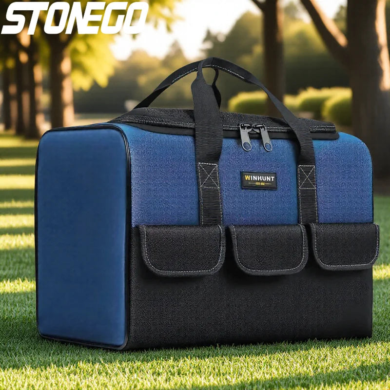 A blue and black heavy duty tool bag with reinforced base and multiple pockets resting on green grass.
