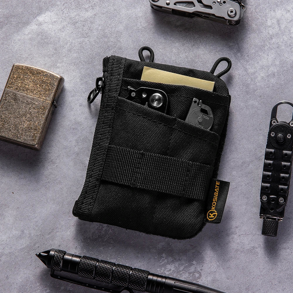 Bolsa organizadora diaria negra con múltiples compartimentos y un pequeño cuchillo sobre una superficie gris.