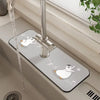 A silver faucet mat with a white rabbit and penguin design is installed on a sink.