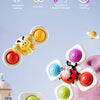 A colorful spinning suction cup bath toy featuring an animal design, shown in various colors on a soft fabric surface.