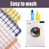 A stack of plaid kitchen towels next to a white washing machine with cleaning liquids.