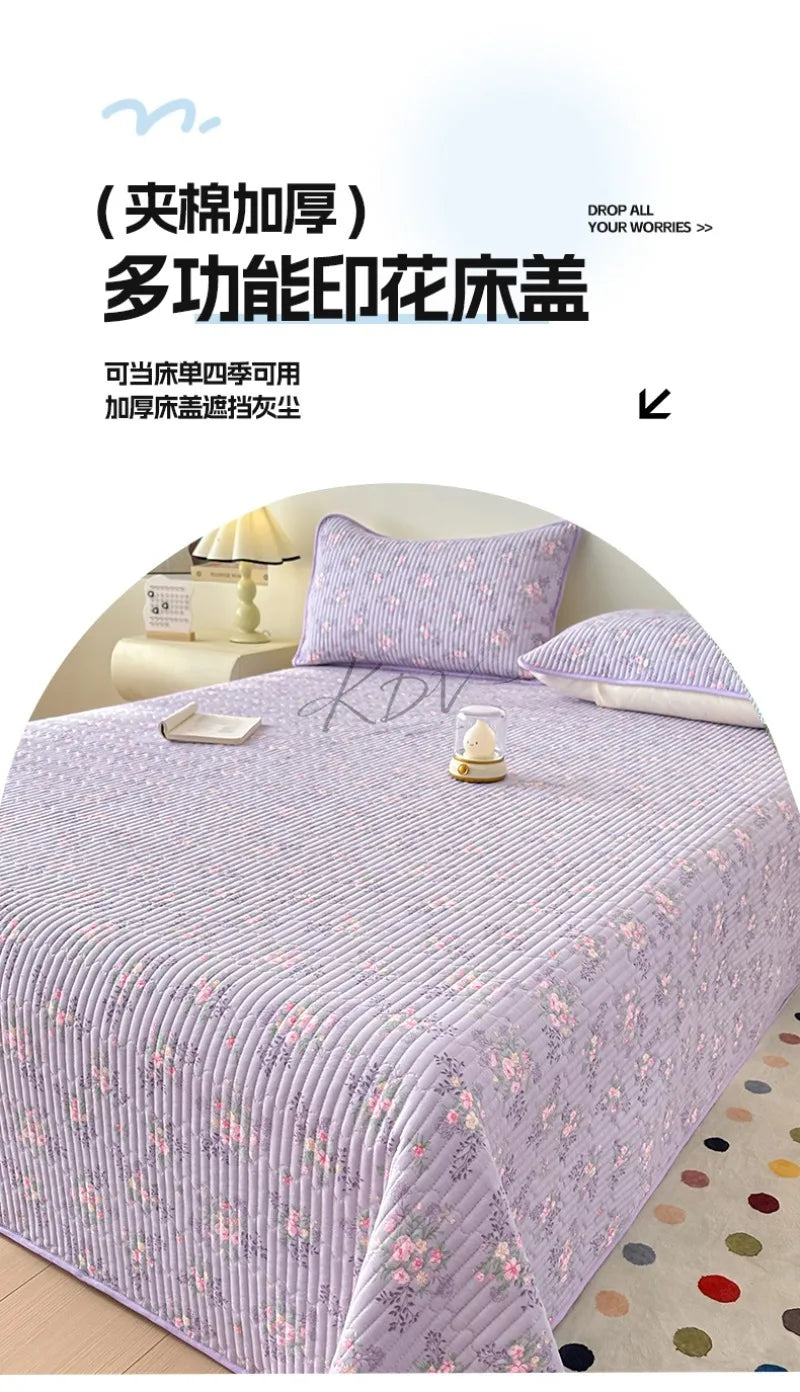 A purple floral quilted bedspread with a textured pattern is displayed on a bed, featuring a dust-proof cover.
