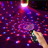 A hand is operating a remote control device that projects a colorful light beam onto a pattern of glowing dots.