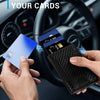 Eine Hand hält eine blaue Karte und eine schwarze, schlanke Aluminium-Kartenträger-Geldbörse im Innenraum eines Autos.