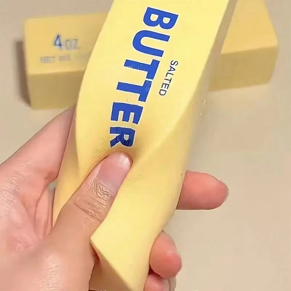 A hand holds a yellow butter stick squishy fidget toy labeled salted.