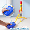 A hand squeezes a blue toy rocket launcher, demonstrating the product for kids.
