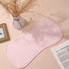 A pink baby burp cloth is displayed on a light background next to dried floral arrangements and a picture frame.