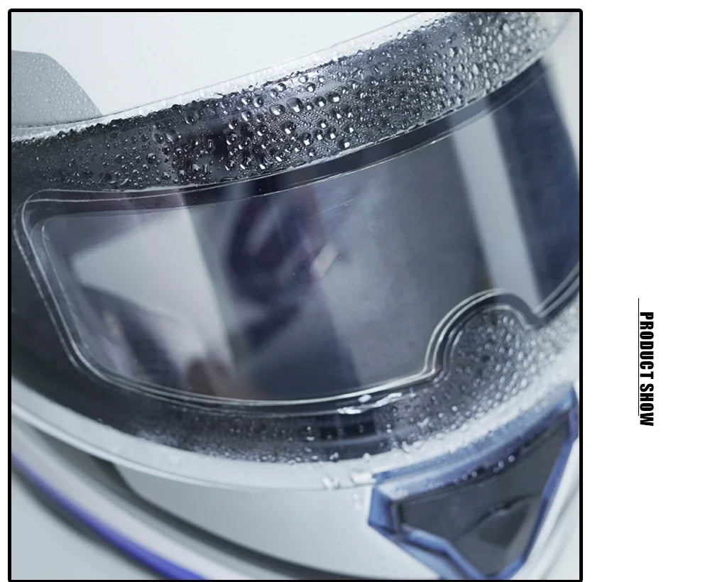 Close-up view of a motorcycle helmet with anti-fog and rain shield film applied, showing water droplets on the surface.