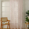 Pink ruffled lace sheer curtains hanging in a white-framed window with a wooden chair nearby
