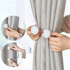 Hands are shown using pearl magnetic curtain clips to hold a gray fabric curtain.