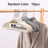 Ten random color velvet non-slip hangers hanging on a wooden rod next to a coat.