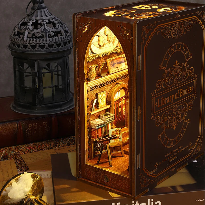 A wooden book nook kit with LED lighting displayed next to a decorative lantern.