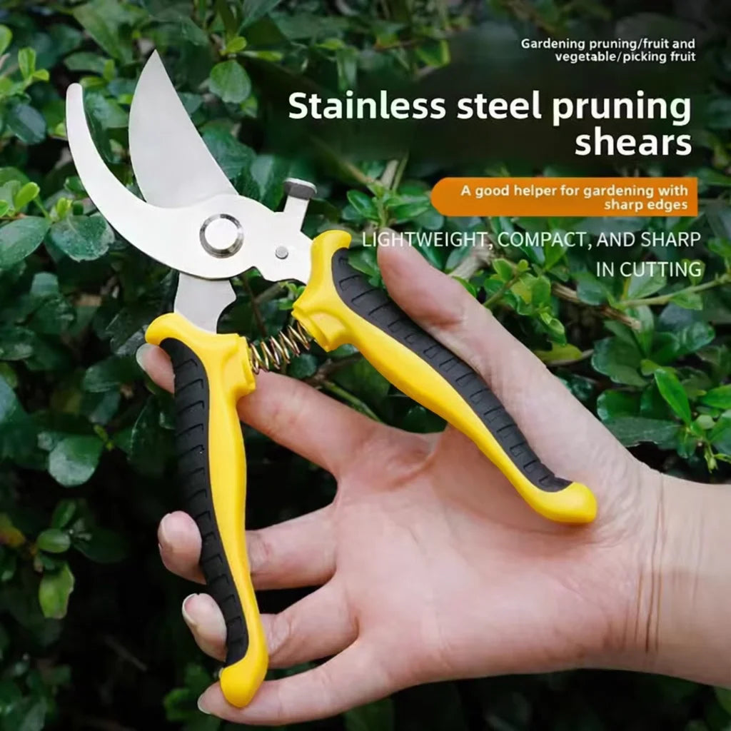 A hand holds a pair of yellow and silver stainless steel pruning shears against a green garden background.
