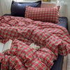 A red and black plaid bedding set featuring a duvet cover, flat sheet, and pillowcases displayed on a bed.